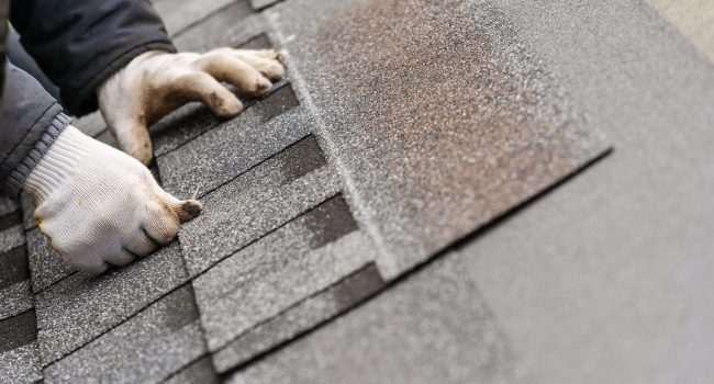 Roofer installing tile on roof of new house under construction